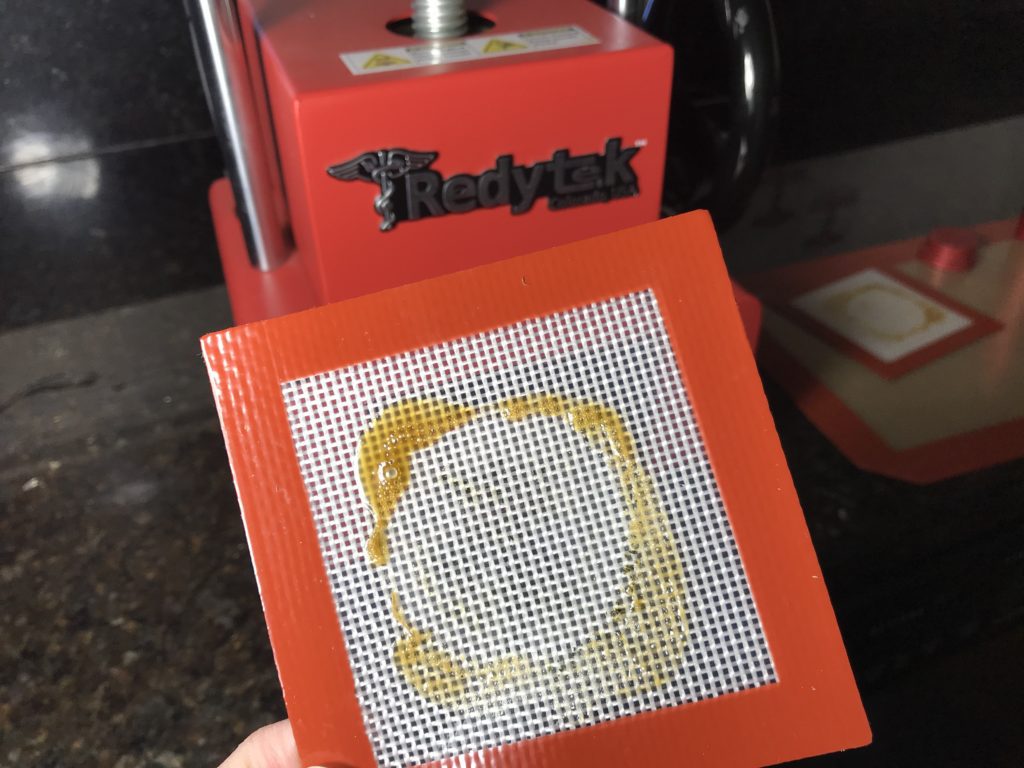 Turning Orange Dispensary flower into gold solventless concentrate using Rosin technique and Redytek rosin press Massachusetts